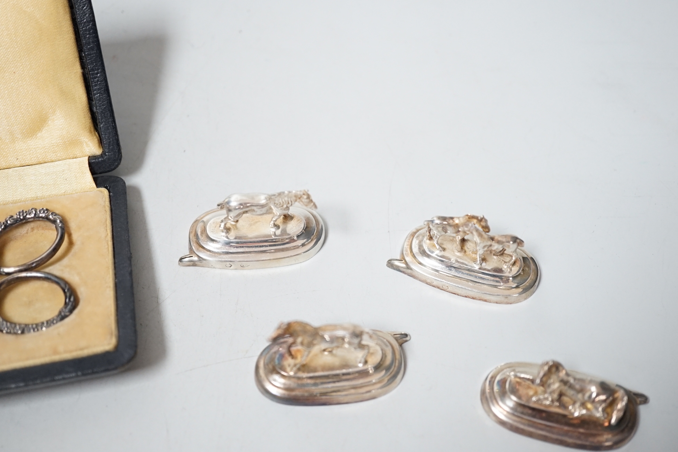 Six assorted Spanish white metal horse menu holders, 43mm, a cased necessaire set, a cigar cutter and a French white metal spoon with hand terminal.